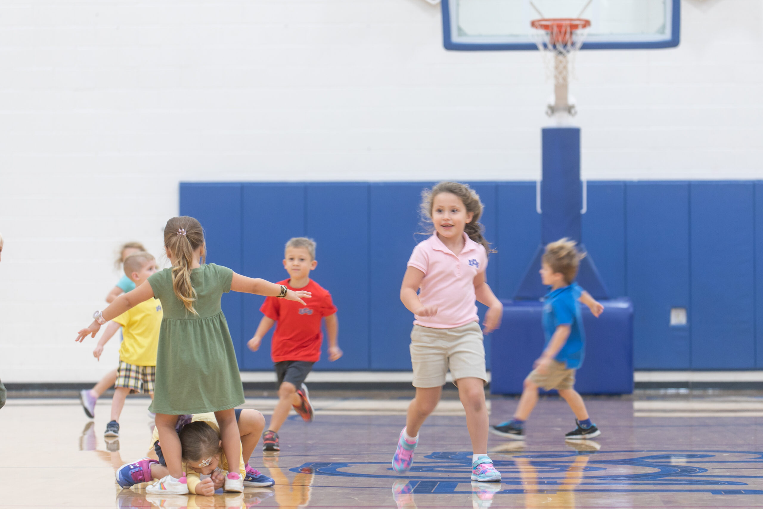 Elementary children running around the basketball court playing during physical education